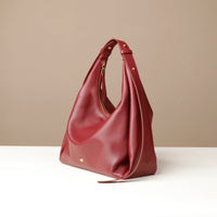 Red handbag on a white surface with a beige background