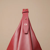 Red handbag with a strap featuring a logo on a beige background