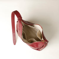 Red handbag with a visible zipper on a light beige background