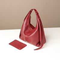 Red handbag and matching pouch on a white surface with a beige background