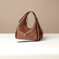 Side view of a brown leather Mini Mia Minimale Danilos handbag with a strap on a beige background