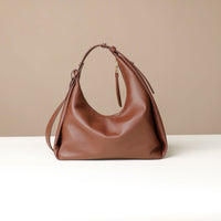 back view of a brown leather Mini Mia Minimale Danilos handbag with a strap on a beige background