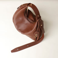 upper view view of a brown leather Mini Mia Minimale Danilos handbag with a strap on and gold accents on a beige background