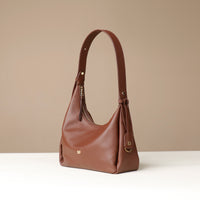 side view of a brown leather Mini Mia Minimale Danilos handbag with a strap handle on a beige background