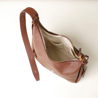 upper view of an open brown leather Mini Mia Minimale Danilos handbag with a strap on a beige background