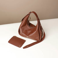 Brown Danilos Mini Mia Minimale Jr handbag and matching wallet on a white surface with a beige background