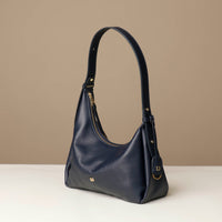 side view of a marine blue leather Mini Mia Minimale Danilos handbag with a handle strap on a beige background
