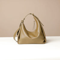 back view of a olive green leather Mini Mia Minimale Danilos handbag with a strap on a beige background