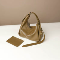 Olive green Danilos Mini Mia Minimale Jr handbag and matching wallet on a white surface with a beige background