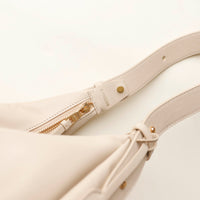 Close-up of a white leather bag with a gold zipper and 'Danilos' branding on a white background