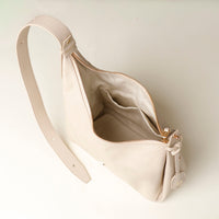 upper view of an open white leather Mini Mia Minimale Danilos handbag with a strap on a beige background