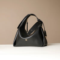 Side view of a Black leather Mini Mia Minimale Danilos handbag with a strap on a beige background