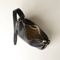 upper view of an open Black leather Mini Mia Minimale Danilos handbag with a strap on a beige background