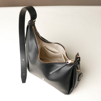 upper view Black leather Danilos handbag that is opened with a gold zipper on a white background