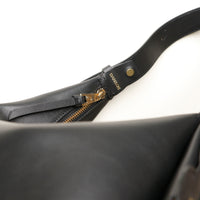 Close-up of a black leather bag with a gold zipper and 'Danilos' branding on a white background