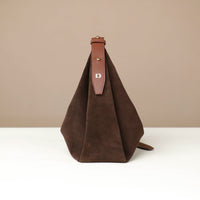 Brown suede bag with leather strap on a beige background