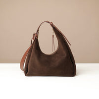 Brown leather handbag on a white surface with a beige background