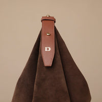 Brown leather strap with a 'D' logo on a brown fabric background