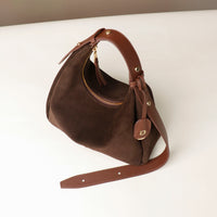 Brown handbag with a strap on a white surface