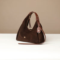 Brown handbag with a visible brand logo on a beige background