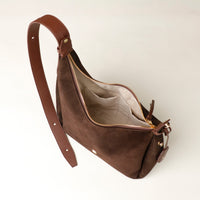Brown leather handbag with a visible zipper on a light beige background