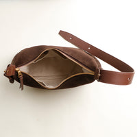 Brown leather bag with a strap on a white background