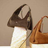 Two brown handbags on a textured surface with a neutral background