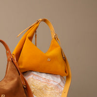 Yellow handbag with a brand logo on a textured surface against a brown background