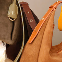 Close-up of three brown leather handbags with visible brand logo.