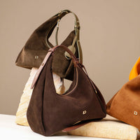 Brown suede handbag on a textured surface with a neutral background