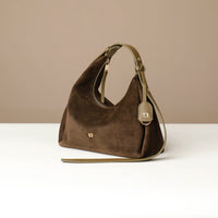 Brown handbag with a strap on a white surface and beige background