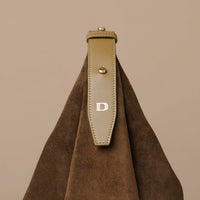 Brown leather strap with a gold buckle on a brown background