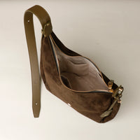 Brown suede handbag with gold zipper on a light gray background