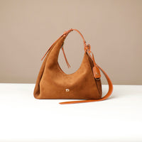 Brown handbag with a strap on a white surface and beige background