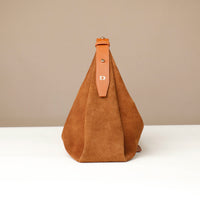 Brown suede handbag with leather strap on a beige background