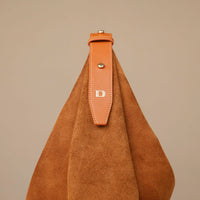 Brown suede handbag with a leather strap on a beige background