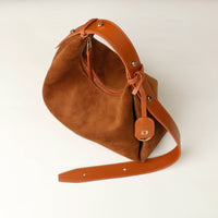 Brown leather handbag with a strap on a white background