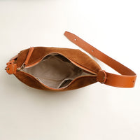 Brown leather bag with a strap on a light beige background