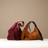 Two handbags, one red and one brown with black strap, on a beige background.