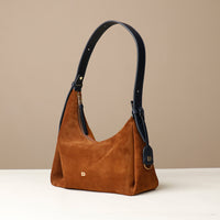Brown handbag with black handle on a beige background