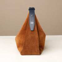 Brown suede handbag with a blue strap on a beige background
