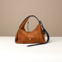 Brown handbag with a black strap on a beige background