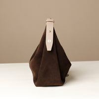 Brown handbag with a beige strap on a beige background