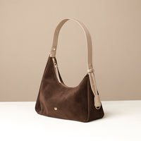 Brown handbag with beige strap on a beige background