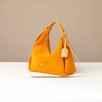 Yellow handbag on a white surface with a beige background
