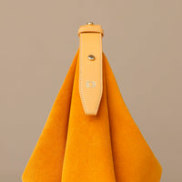 Mustard yellow handbag with a strap on a beige background