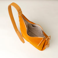 Yellow suede bag with a strap on a white background