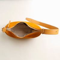 Yellow leather bag with a strap on a light beige background