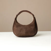 Brown suede leather danilos handbag on a white surface with a beige background