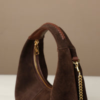 close up of a Brown leather danilos  handle bag with gold chain detail on a neutral background